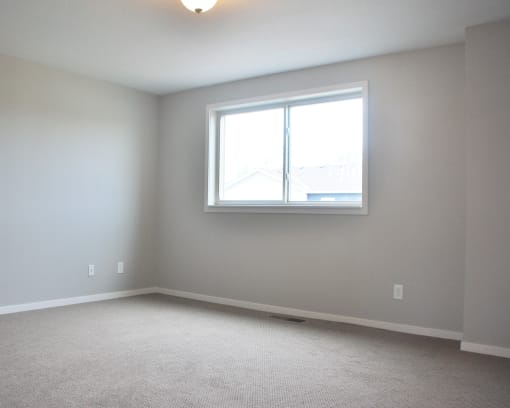 a bedroom with a large window and a carpeted floor