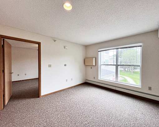 A room with a carpeted floor, a window, and a door.