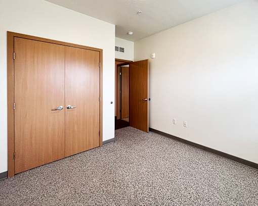 A room with two wooden doors and carpeted floor.