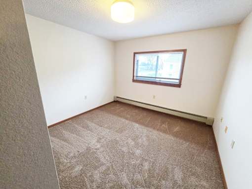 A room with a carpeted floor and a window.