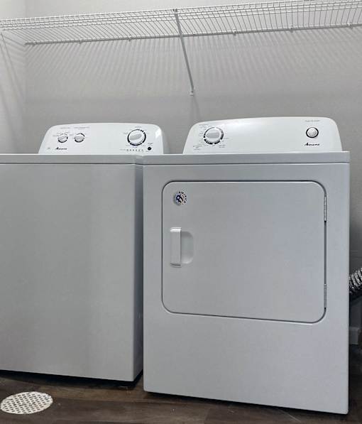 Two white front loading washing machines in a laundry room.
