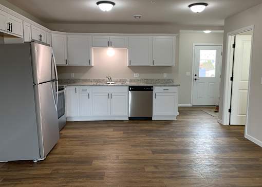 A kitchen with white cabinets and a wooden floor.