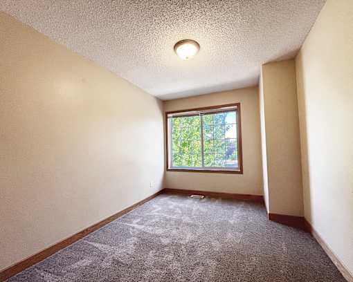 A room with a window and carpeted floor.