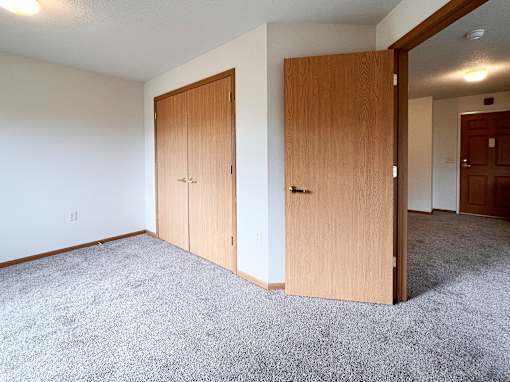 A room with two wooden doors and carpeted floor.