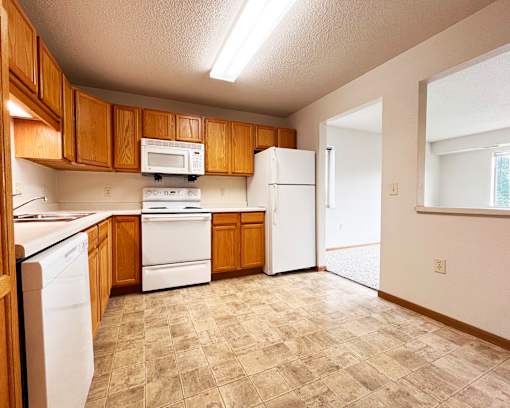 A kitchen with white appliances and wooden cabinets.