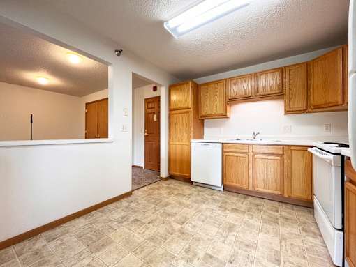 A kitchen with white appliances and wooden cabinets.