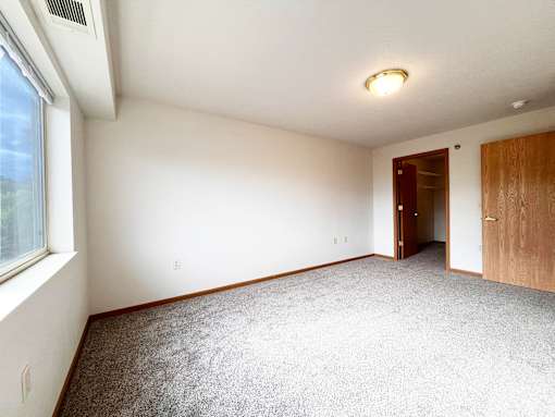 A room with a carpeted floor, a window, and a door.