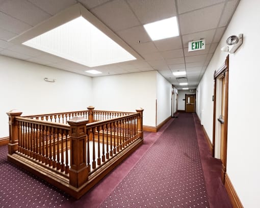 a hall with a wooden staircase and a exit sign