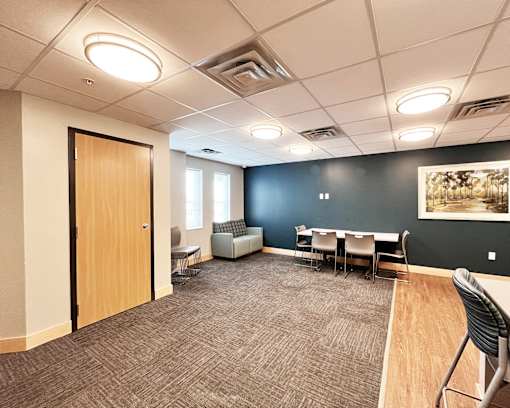 A conference room with a carpeted floor, a wooden table, and chairs.