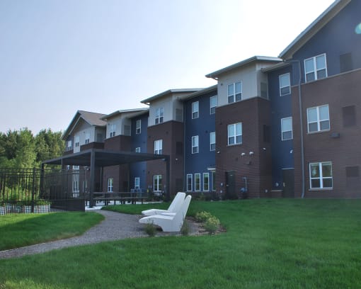 a grassy area with a white chair in front of an apartment building