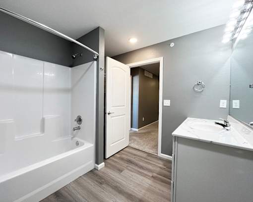 A bathroom with a white tub and sink, and a white door.