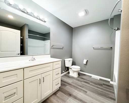 A bathroom with a white counter top and a white toilet.
