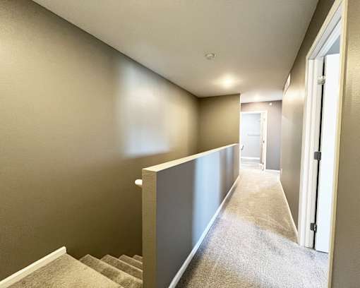 A hallway with a staircase on the left and a door on the right.