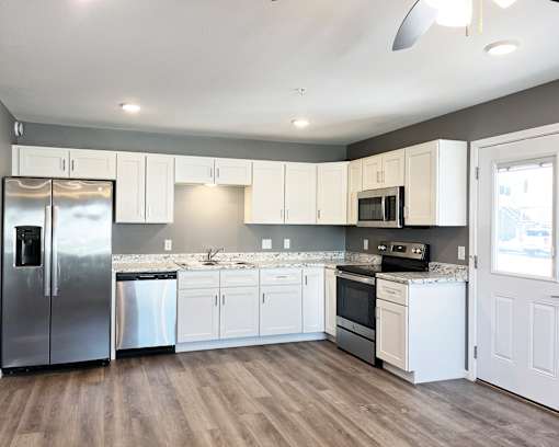 A kitchen with white cabinets and a wooden floor.
