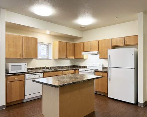 A kitchen with white appliances and wooden cabinets.