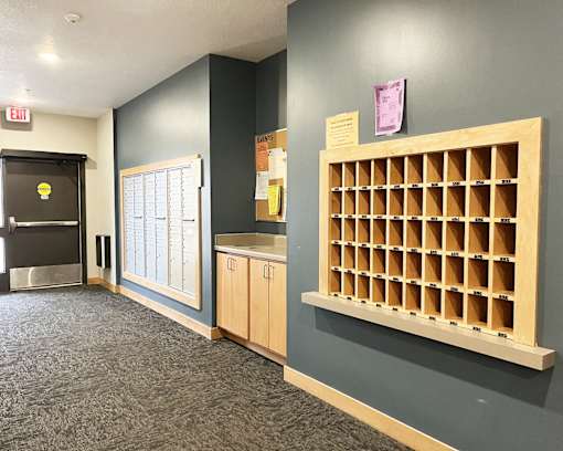 A long hallway with a bulletin board on the wall.