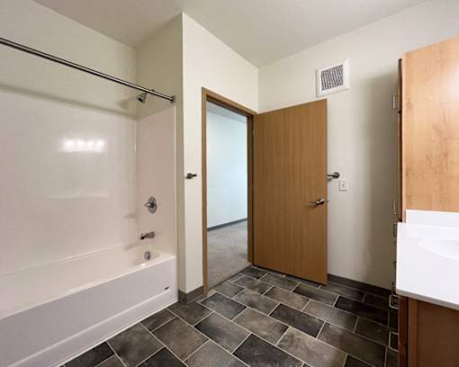A bathroom with a tiled floor and a white bathtub.