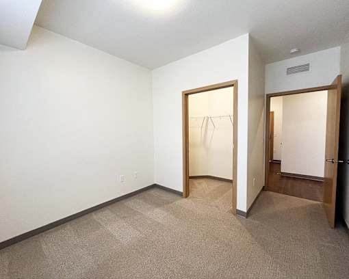 A room with a carpeted floor and two open doors.