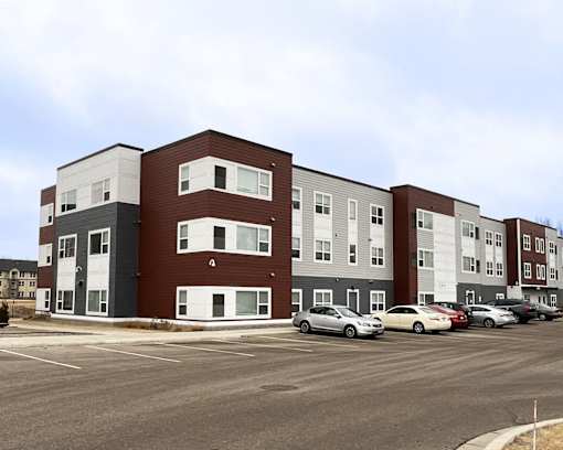 A parking lot in front of a multi-story apartment building.