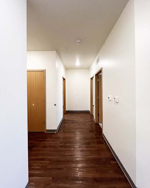 A long hallway with wood floors and white walls.