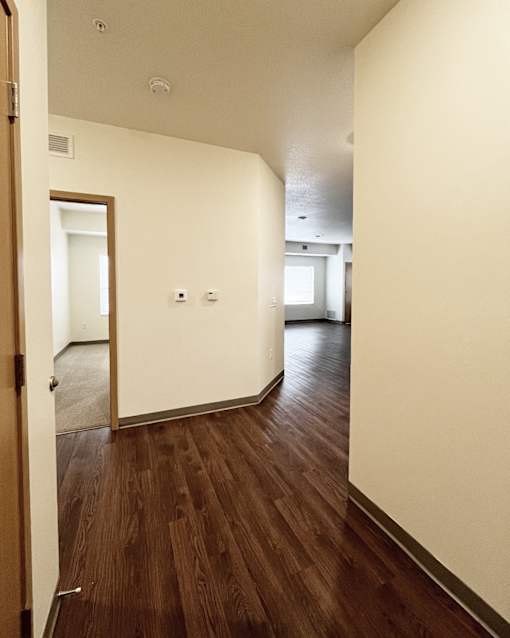 A hallway with wood floors and white walls.