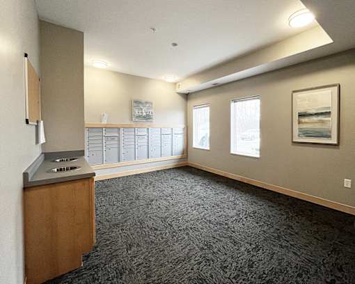 A room with a carpeted floor, a wooden cabinet, and a framed picture on the wall.