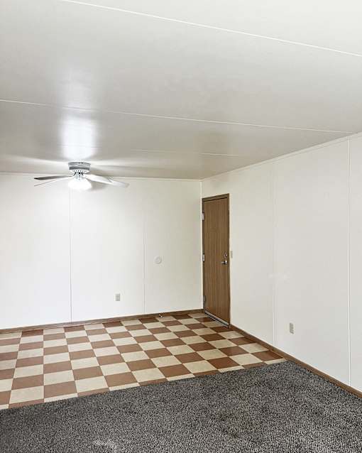 an empty living room with a checkered floor and a ceiling fan