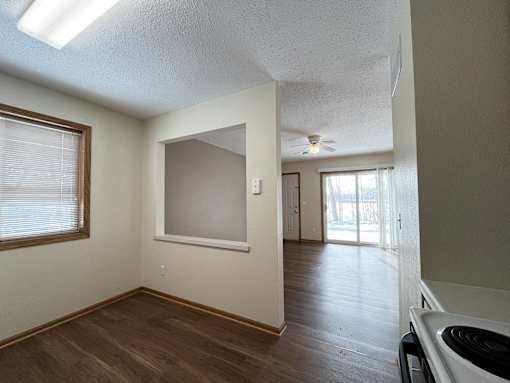 an empty kitchen and living room with wood flooring and a ceiling fan