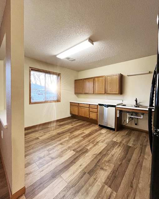 A kitchen with wooden floors and a black refrigerator.