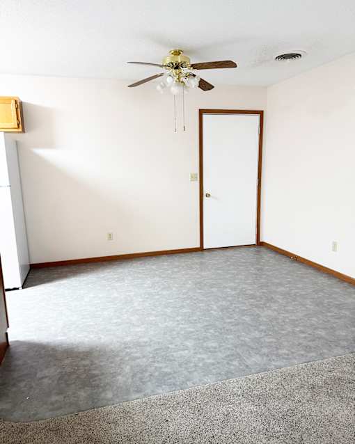 A room with a ceiling fan and a door.
