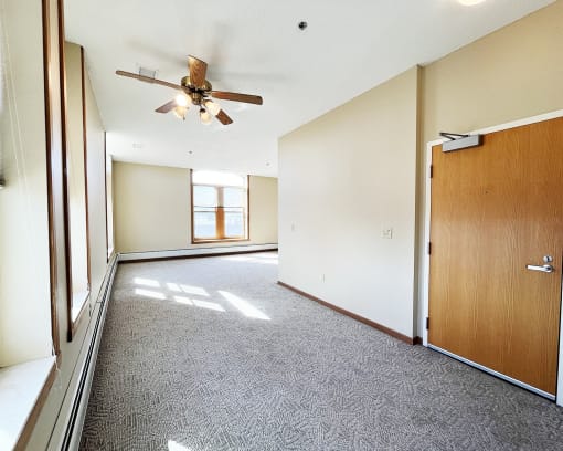 an empty living room with a ceiling fan