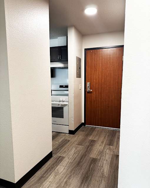 A kitchen with a wooden door and a white wall.