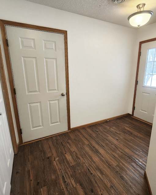 A room with a white door and brown wood flooring.