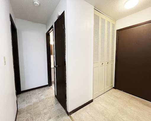 an empty hallway with two doors and a closet