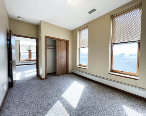 an empty living room with three windows and a door