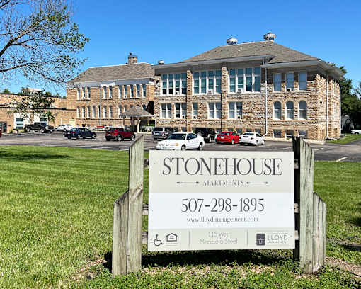 A sign for Stonehouse Apartments is in front of a brick building.