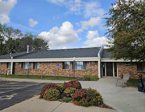 A building with a brick facade and a parking lot in front.