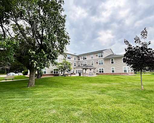 A large grassy area in front of a building with trees on the sides.