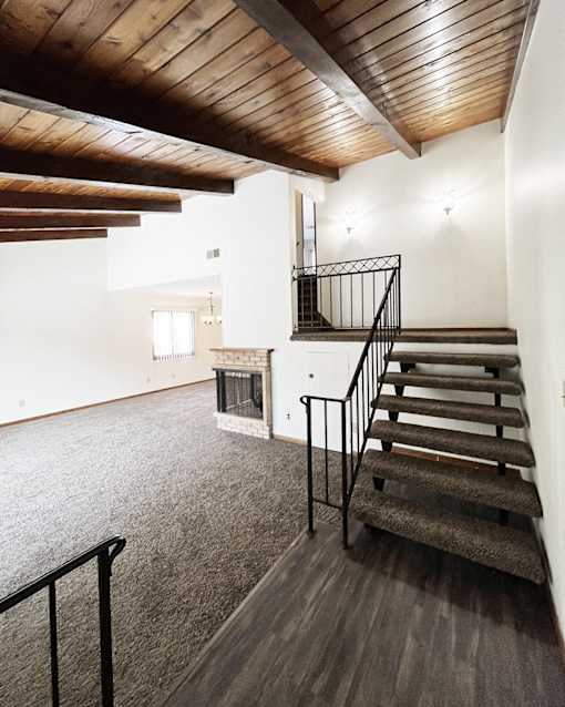 A wooden staircase with a metal railing leads up to a second floor.