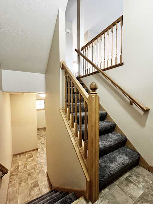 A staircase with a wooden banister and a carpeted stair runner.