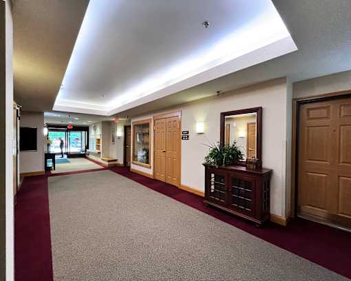 A hallway with a red carpet and wooden doors.