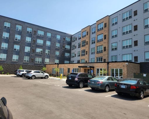 a parking lot with cars in front of an apartment building
