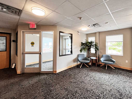 A room with grey carpet and a grey chair.