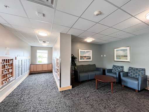 A living room with a grey carpet and a grey couch.