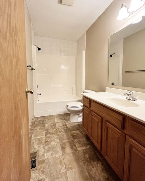 A bathroom with a toilet, sink and mirror.