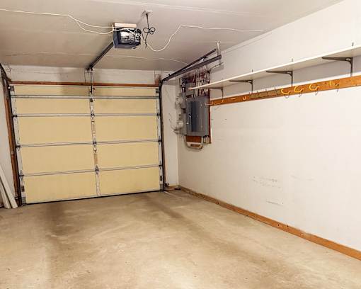 A garage with a closed white door and a wall-mounted TV.
