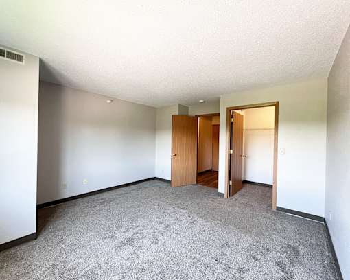 A room with carpeted floor and two wooden doors.