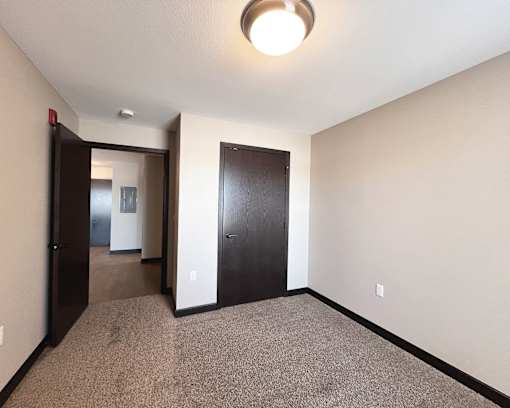 A hallway with a carpeted floor and two doors.