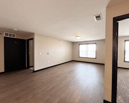 A spacious room with wooden flooring and a large mirror on the wall.