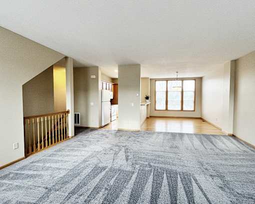 A large, empty room with a carpeted floor and a window.